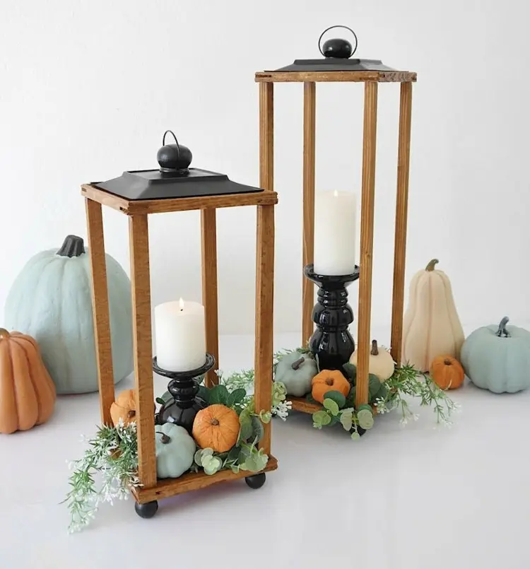 Open lantern fall decoration with candlesticks and wreath of pumpkins and greens