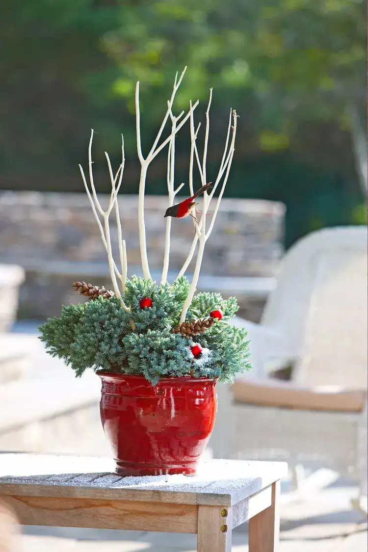 red flower pot in the garden decorated with bird figurines and twigs