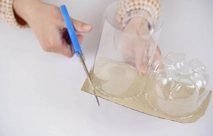 Cut off the excess cardboard at the rim of the plastic bottle pieces