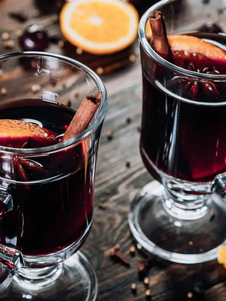 cinnamon sticks and orange slices in glasses with mulled wine
