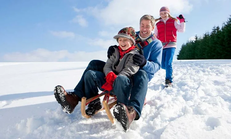 go sledding having fun outdoors family time mum dad and son