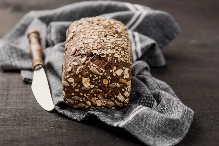 tasty bread with seeds on top grey cloth wooden knife