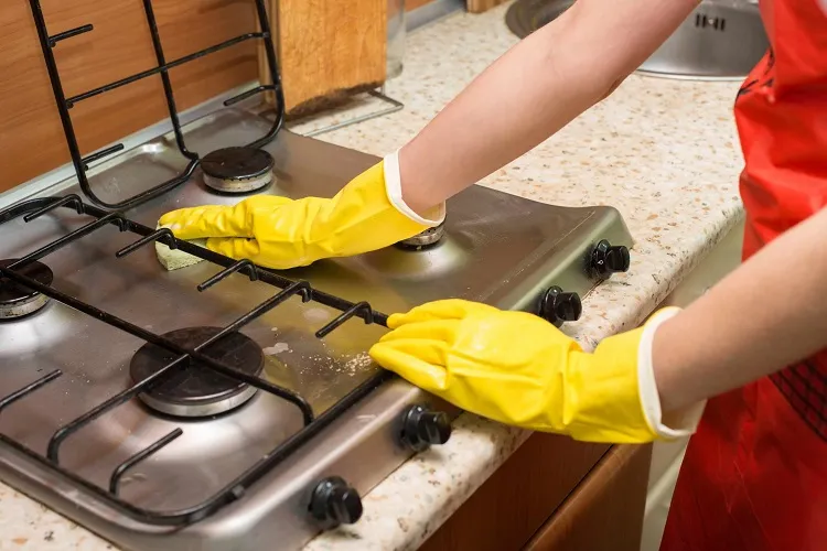 Cleaning-dirt-off-stainless-steel-stove-with-a-sponge