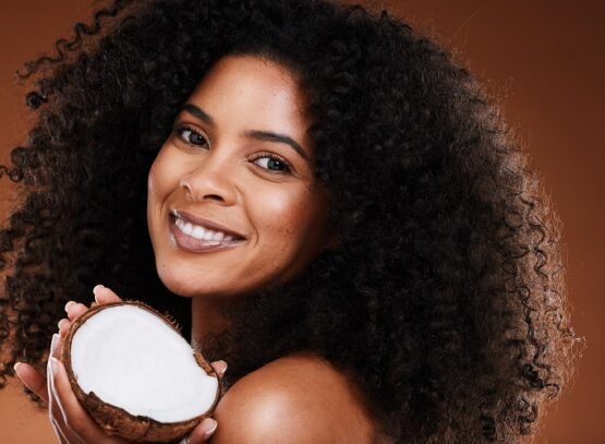 Beauty, coconut and woman with skincare, smile, happy or curls for natural oil and brown studio bac.