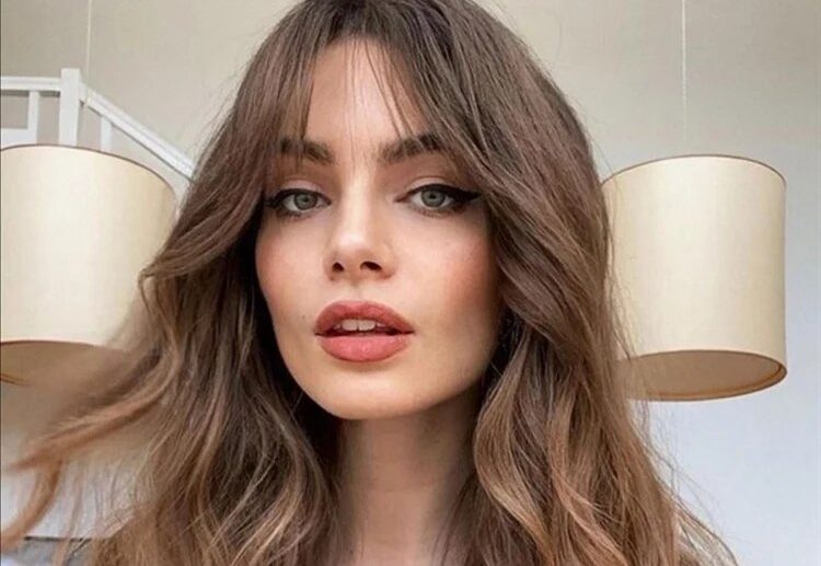 blow dry and round brush styling long hair with curtain bangs