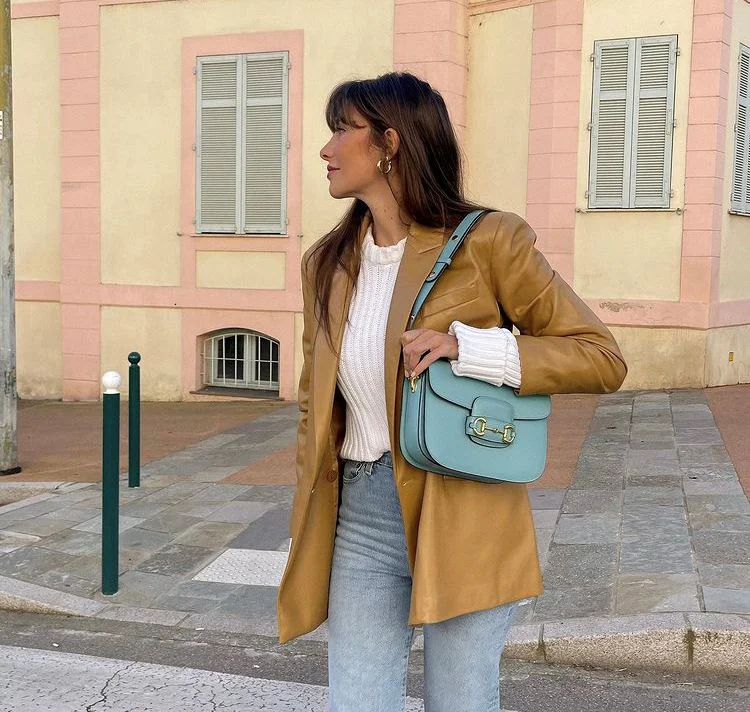 choose accessories with taste medium sized baby blue handbag gold earrings brown leather jacket light jeans
