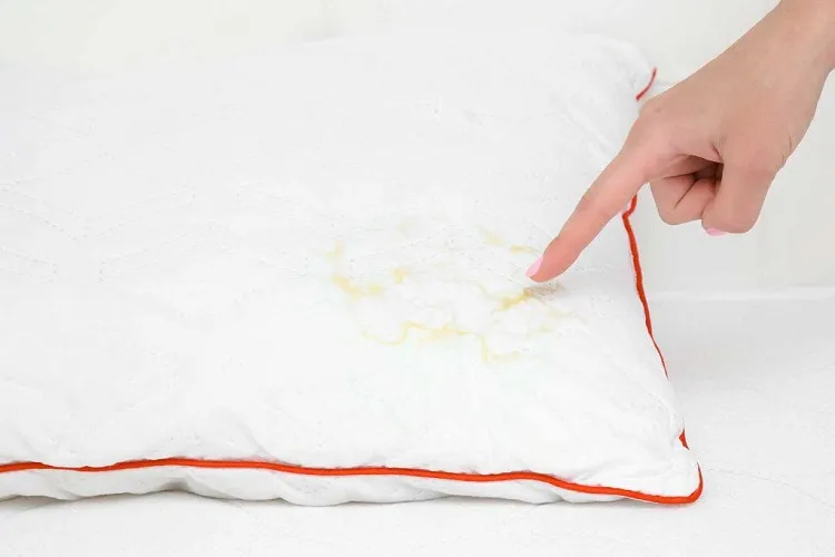womans hand finger pointing to saliva stain on white pillow 1024x683