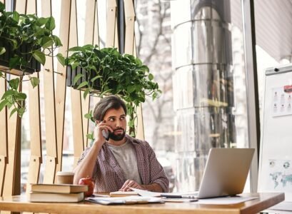 a person who is quietly confident makes the best leader. pensive manager is talking on the phone while sitting in creative office and looking away