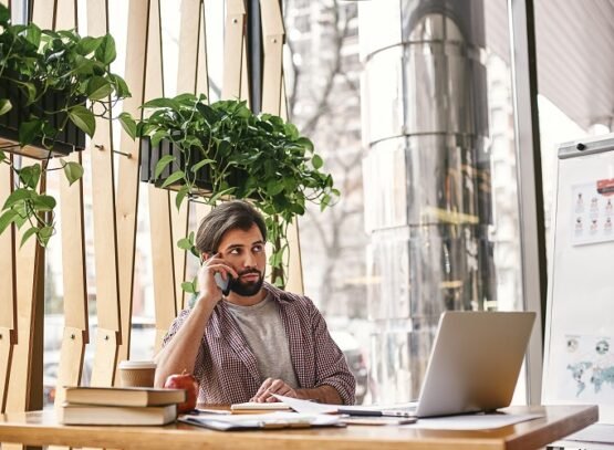 a person who is quietly confident makes the best leader. pensive manager is talking on the phone while sitting in creative office and looking away