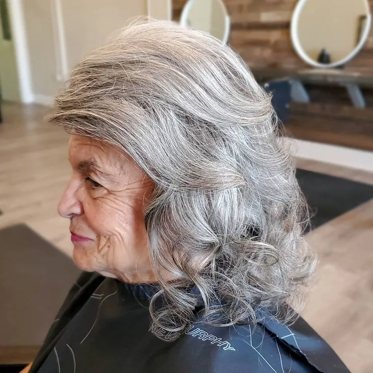 blowout roller set curls side swept bangs medium length layered hairstyle natural gray hair women over 60