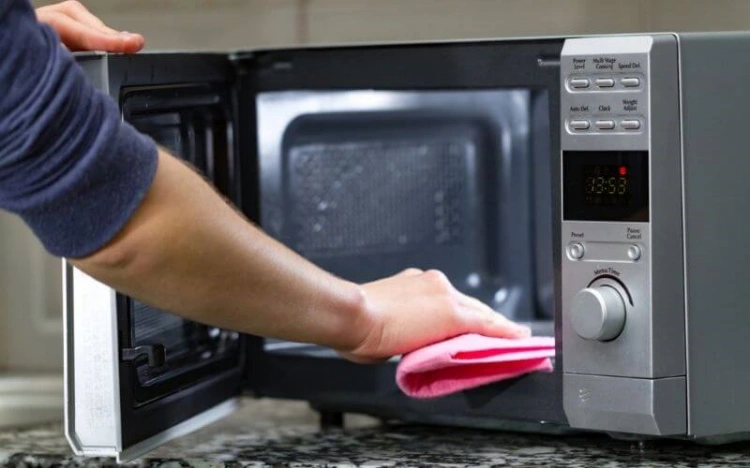 cleaning microwave with lemon and scrubbing with a cloth