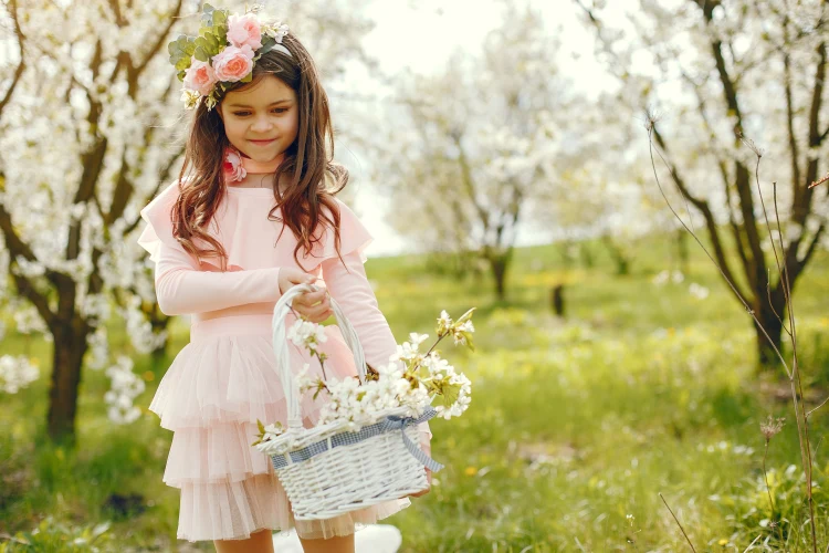 cute little girl in a pink dress holding a basket of flowers