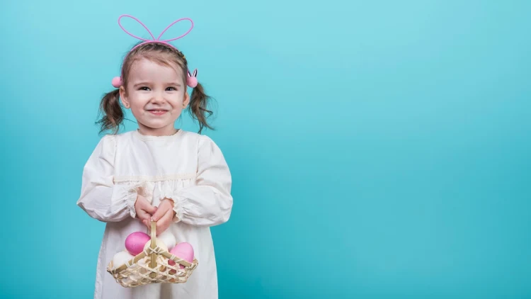 little girl with bunny ears holding a basket of eggs