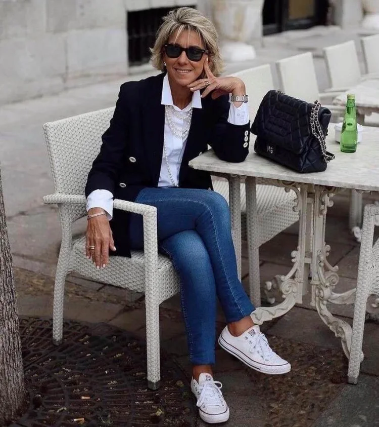 white sneakers after 50 blue jeans white shirt black blazer and purse
