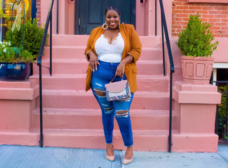 plus size bodysuit model wearing ripped jeans and yellow blazer