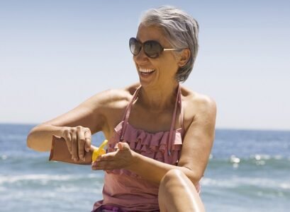 hispanic woman applying sunscreen on beach