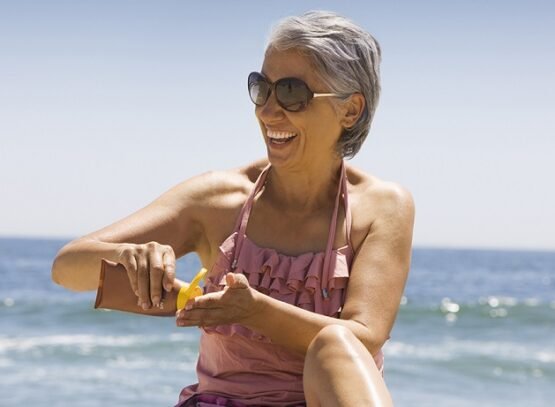 hispanic woman applying sunscreen on beach