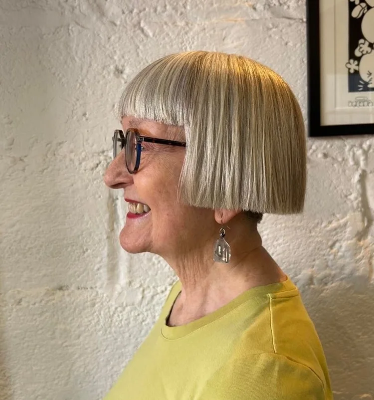 box bob haircut for women over 60 with blunt bangs and glasses