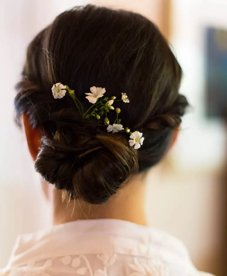 braided low bun with flowers wedding guest hairstyle 2023