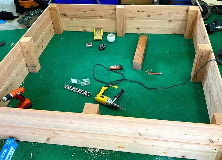 build a sandbox for kids with suitable wooden materials and integrateit in the garden