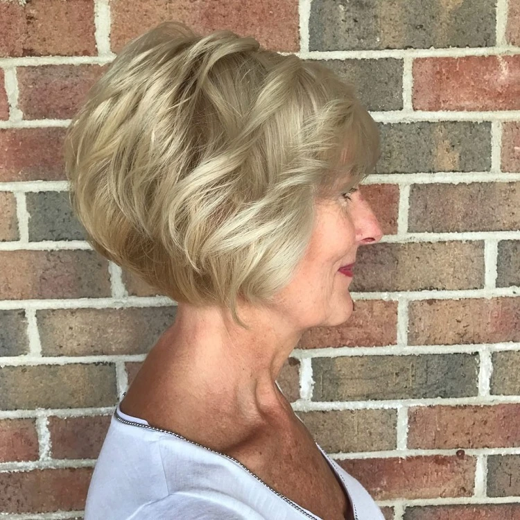 Corte de pelo bob corto para mujeres mayores de 60 años con cabello rizado y flequillo.