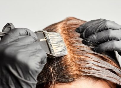 closeup woman hands dyeing hair using a black brush. colouring of white hair at home.