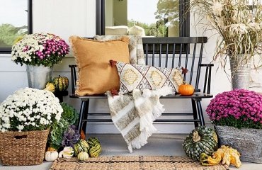fall front porch decor wooden porch boho pillows rattan rug potted mums 2023