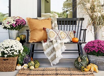 fall front porch decor wooden porch boho pillows rattan rug potted mums 2023