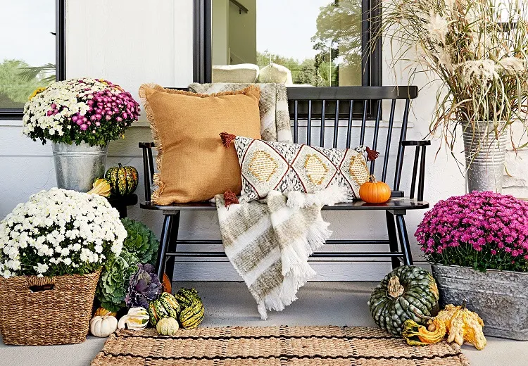 fall front porch decor wooden porch boho pillows rattan rug potted mums 2023