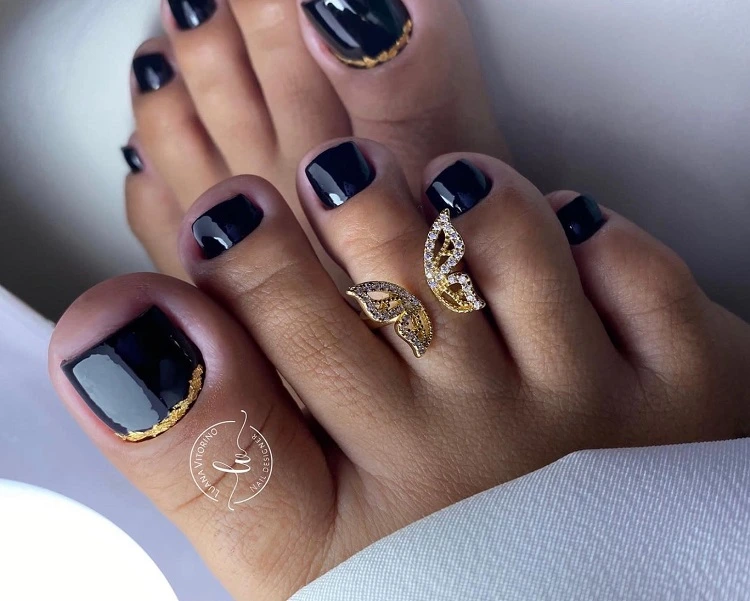 reverse french pedicure with black and gold fall toenail color trends 2023