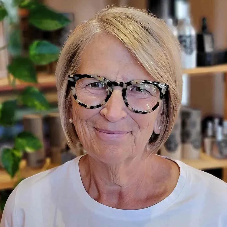 blonde short hairstyle with a deep side part for women over 70 with glasses