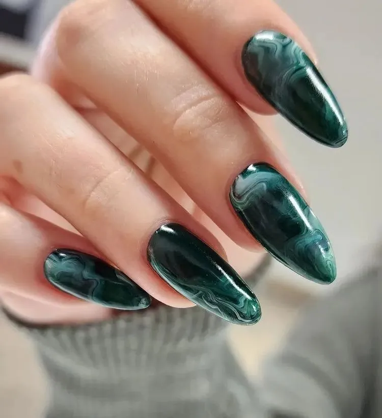 dark green nail art with marble effect on long almond shaped nails