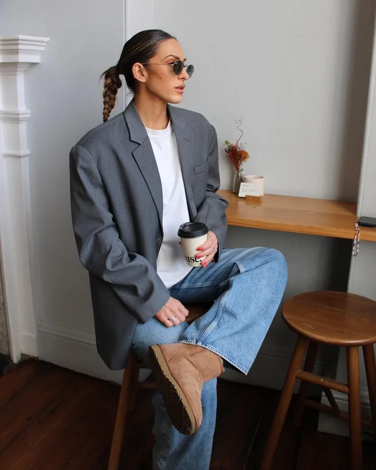 office outfit idea mini classic sheepskin ugg boots baggy blue jeans oversized grey blazer white tee sunglasses slicked back braided ponytail