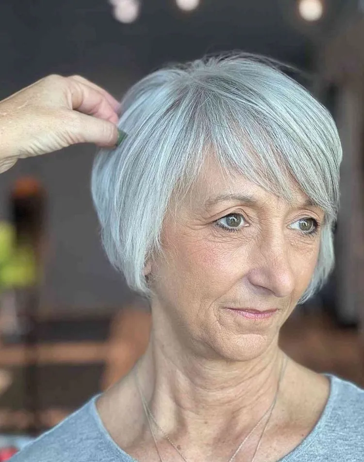 Corte de pelo corto bixie asimétrico con flequillo lateral tenue para mujeres mayores de 60 años.