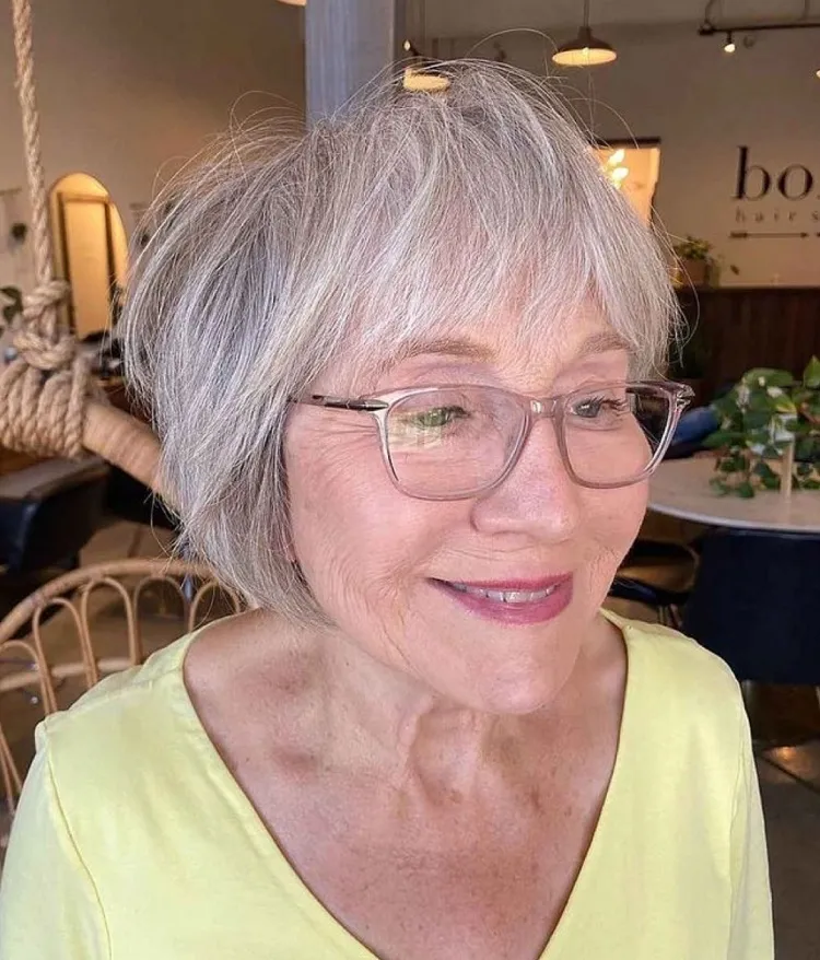 Corte de pelo corto bob para mujeres con canas mayores de 60 años con flequillo y gafas.