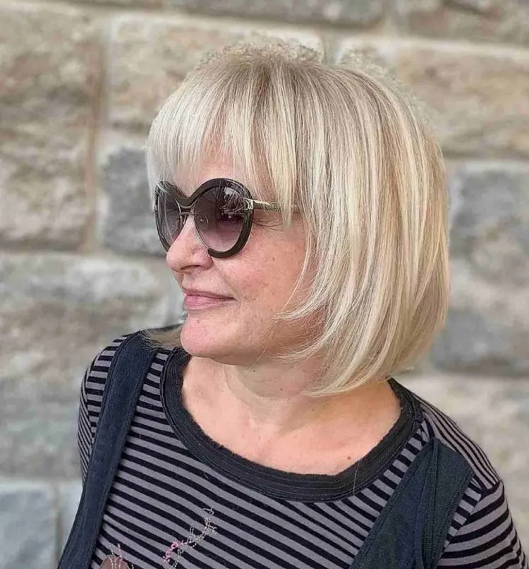 Corte de pelo corto con flequillo y capas que enmarcan la cara para mujeres mayores de 60 años.