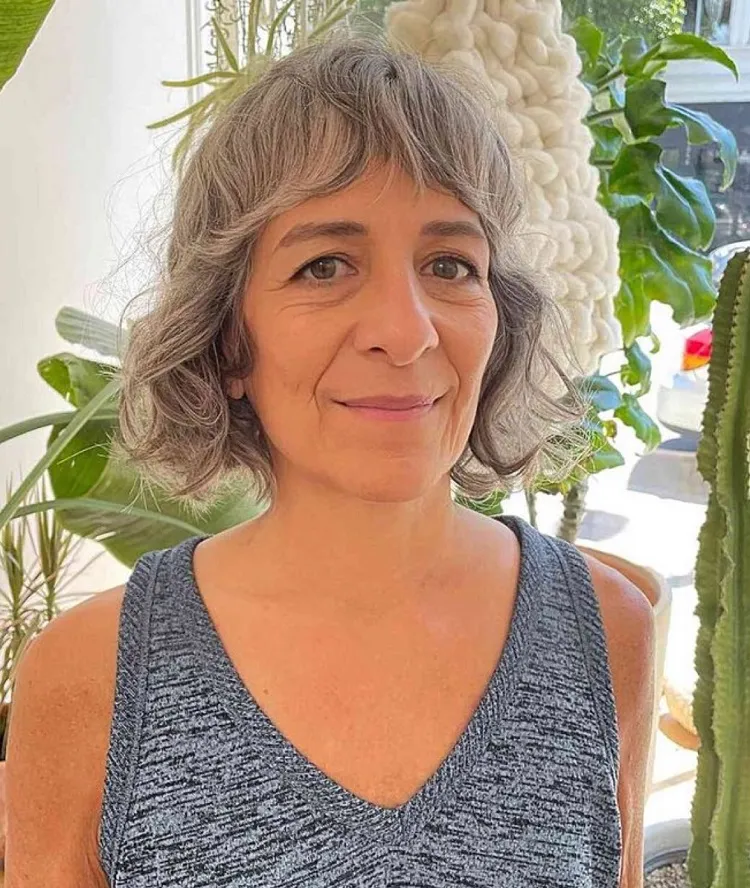 Corte de pelo corto Shag Bob con flequillo de cortina para mujeres mayores de 60 años con cabello ondulado.