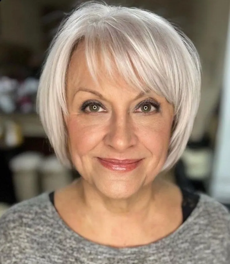 stacked bob cut with wispy bangs for women over 60 with white hair