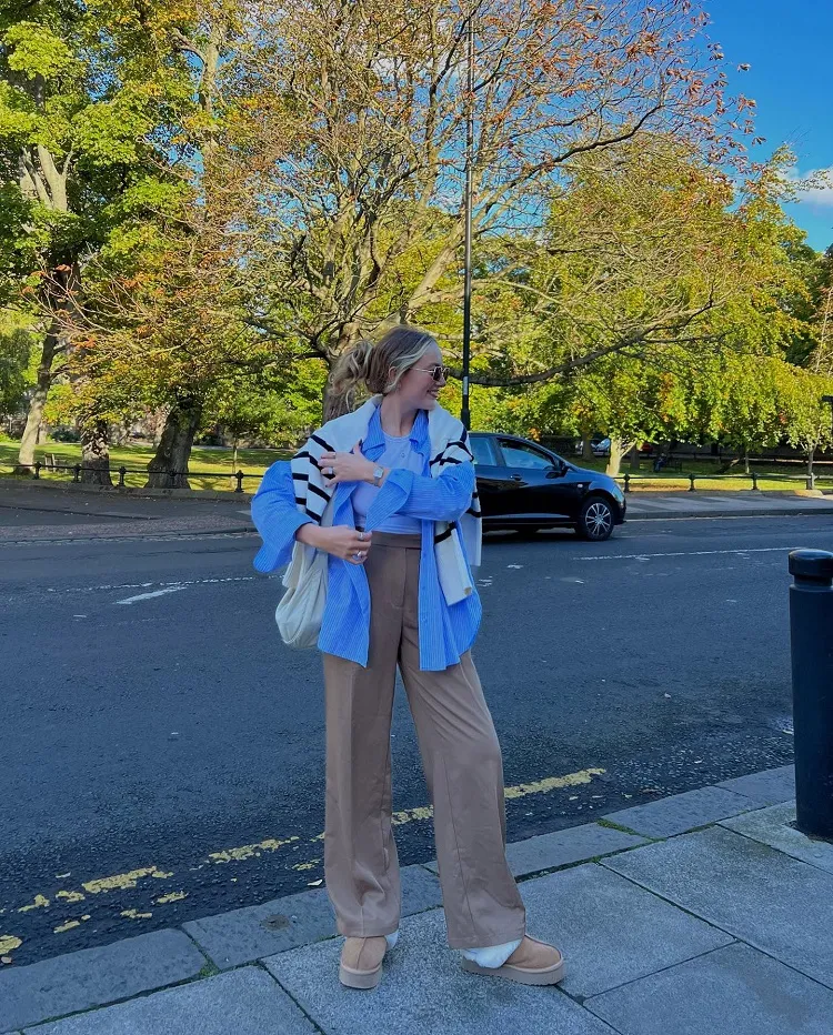styling strap slingback ugg slippers fall office outfit idea high waisted brown wide leg pants blue striped shirt old money sweater messy low bun hairstyle