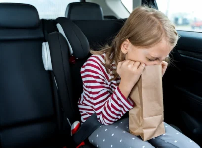 toddler feeling sick in car vomiting in paper bag
