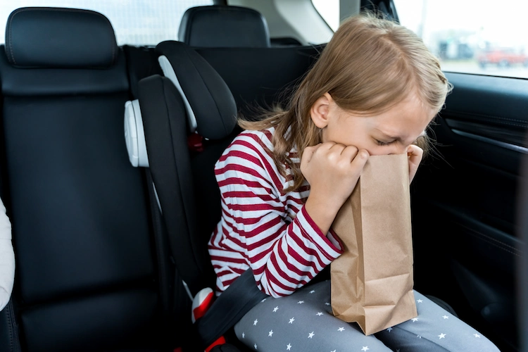 toddler feeling sick in car vomiting in paper bag