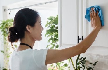 woman cleaning painted wooden kitchen cabinets