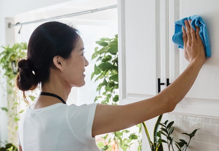 woman cleaning painted wooden kitchen cabinets