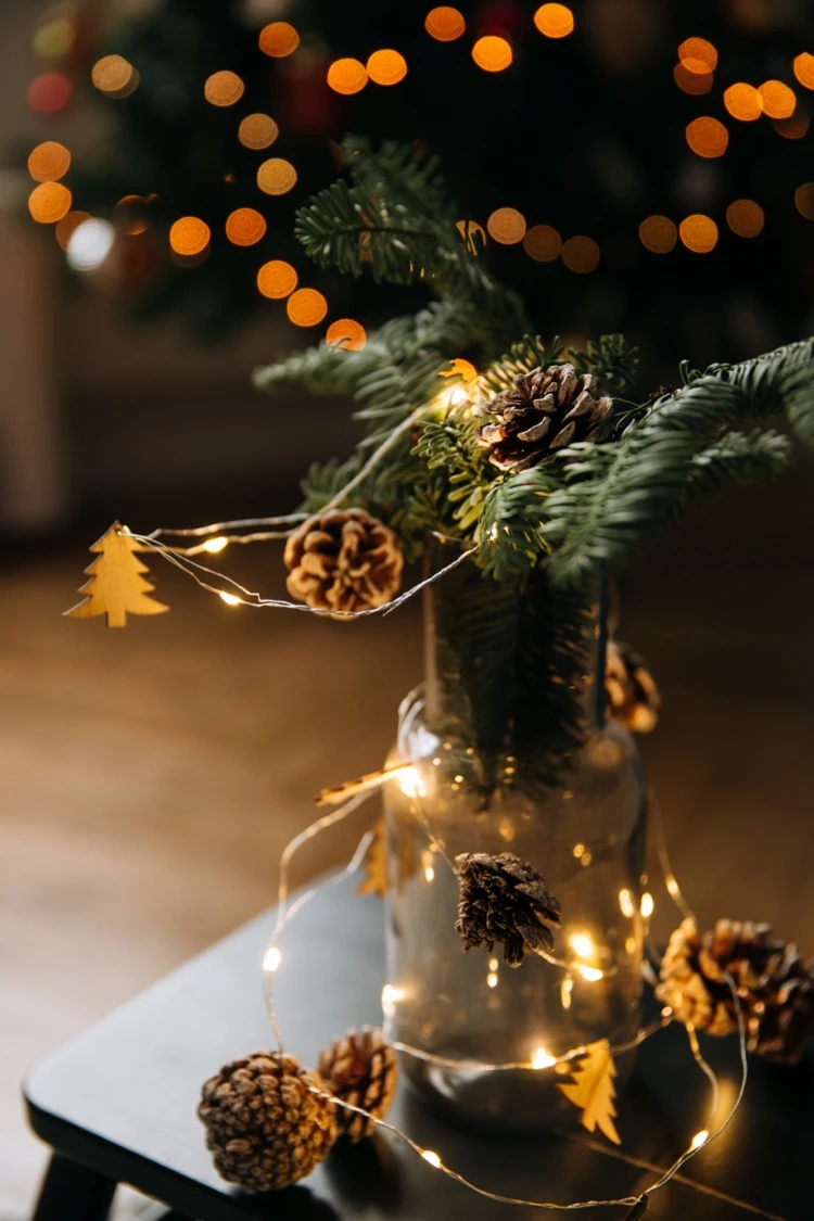 christmas decoration in a glass with fairy lights and pine cones