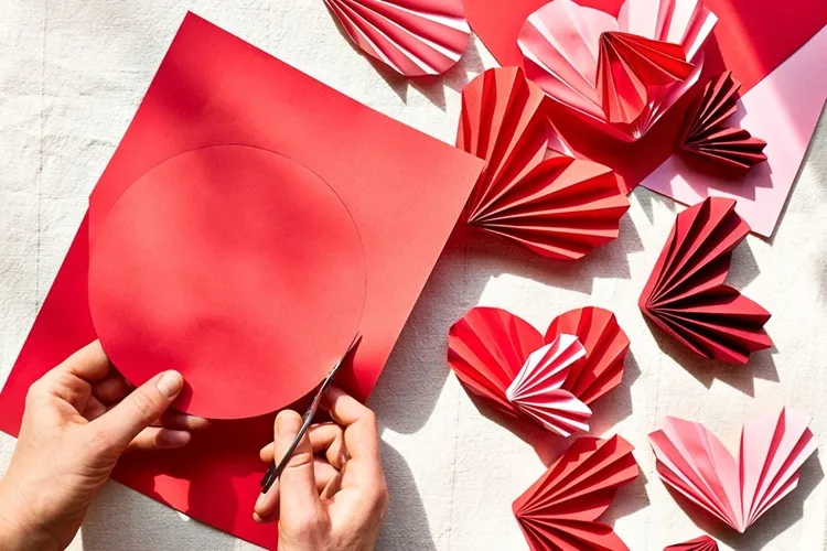 cutting out a circle from a red piece of print paper to make a heart