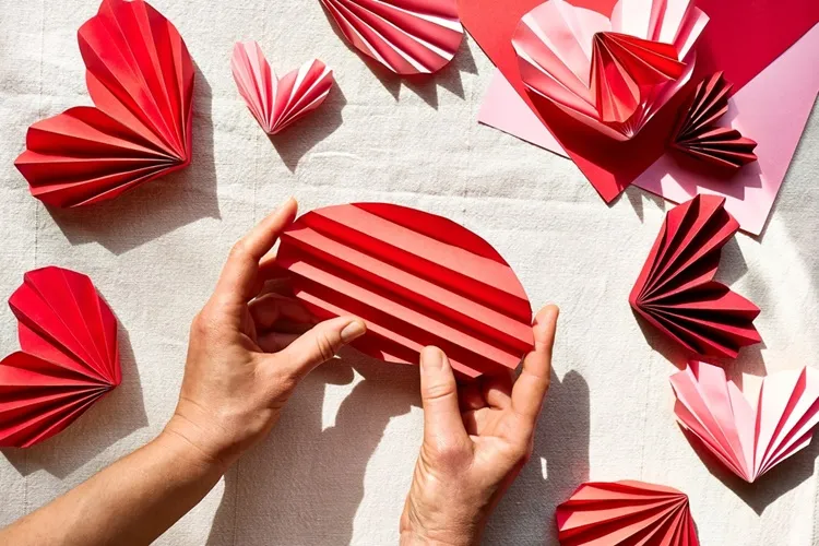 folding a round piece of red print paper into an accordion