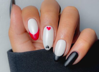 milky white nails with red and black french tips and mini hearts