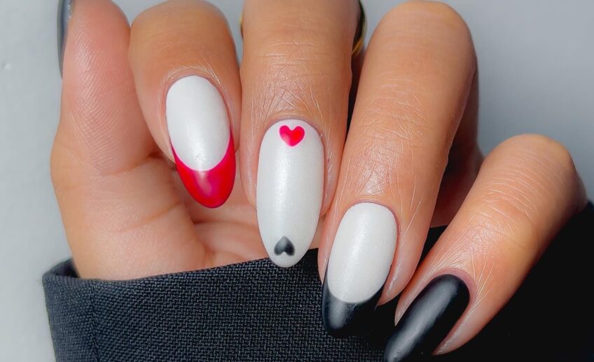 milky white nails with red and black french tips and mini hearts