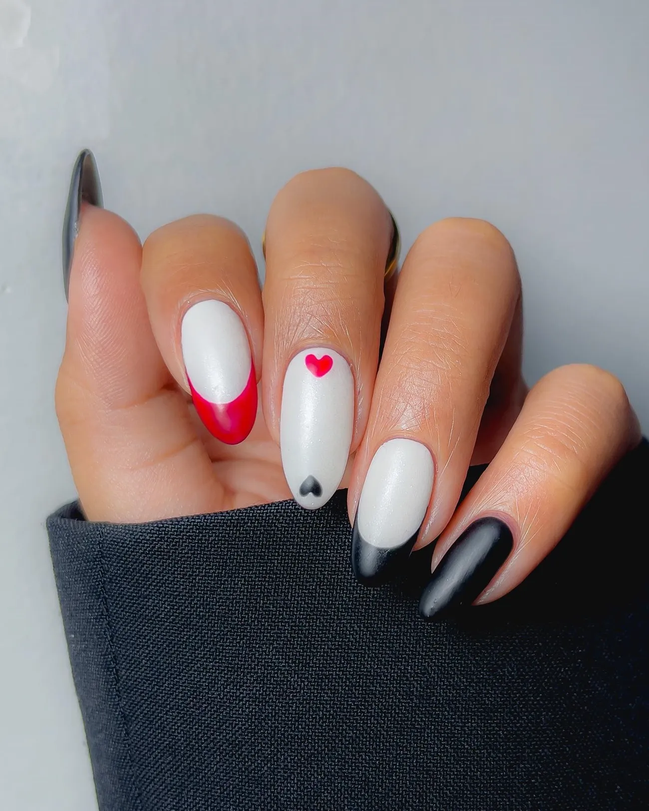 milky white nails with red and black french tips and mini hearts