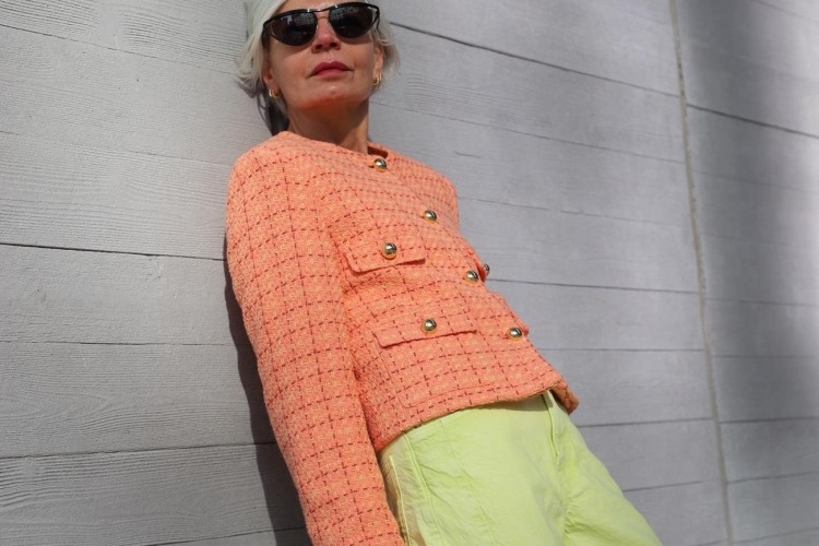 peach fuzz boucle jacket paired with lime green pants and a ontreasting pink bag